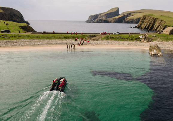 Das Schlauchboot mit den Kreuzfahrtgästen fährt an den Sandstrand von Fair Isle